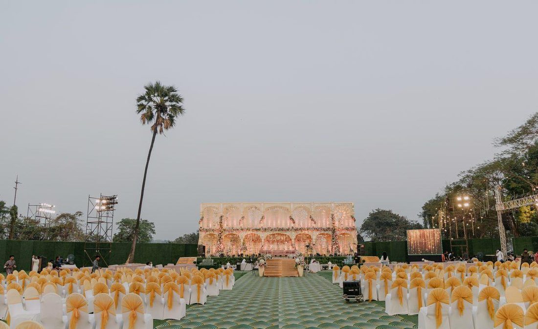 Daytime wedding stage with palm tree and gold bow chairs